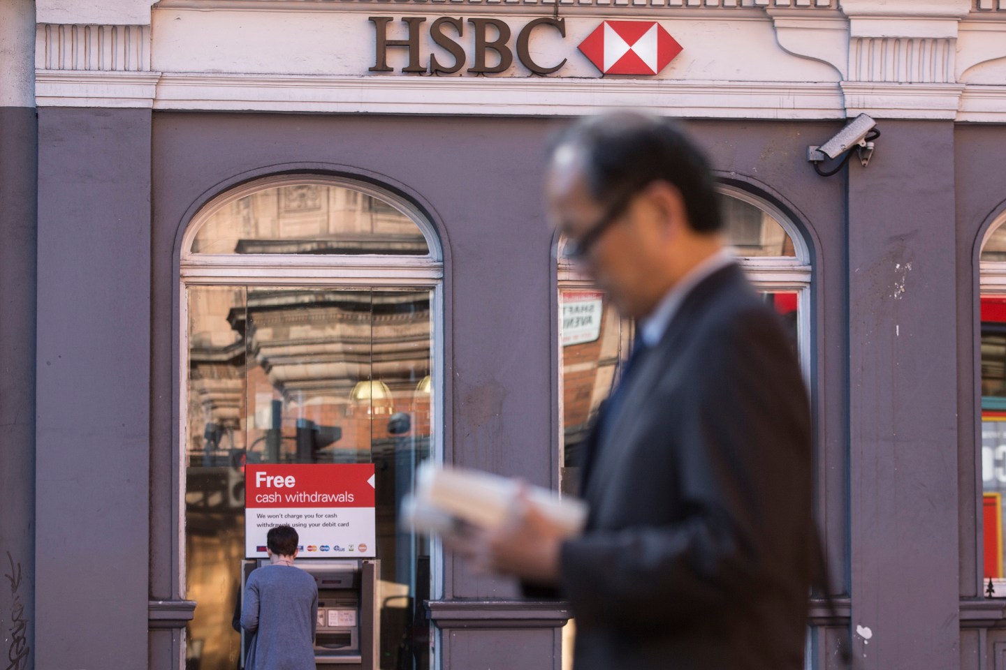 A pedestrian passes an automated teller machine (ATM) outside an HSBC Holdings Plc bank branch in London, U.K., on Tuesday, June 9, 2015. HSBC will eliminate as many as 50,000 jobs through 2017 by shrinking its global reach as Chief Executive Officer Stuart Gulliver seeks to cut annual costs by about $5 billion to restore profit growth. Photographer: Simon Dawson/Bloomberg