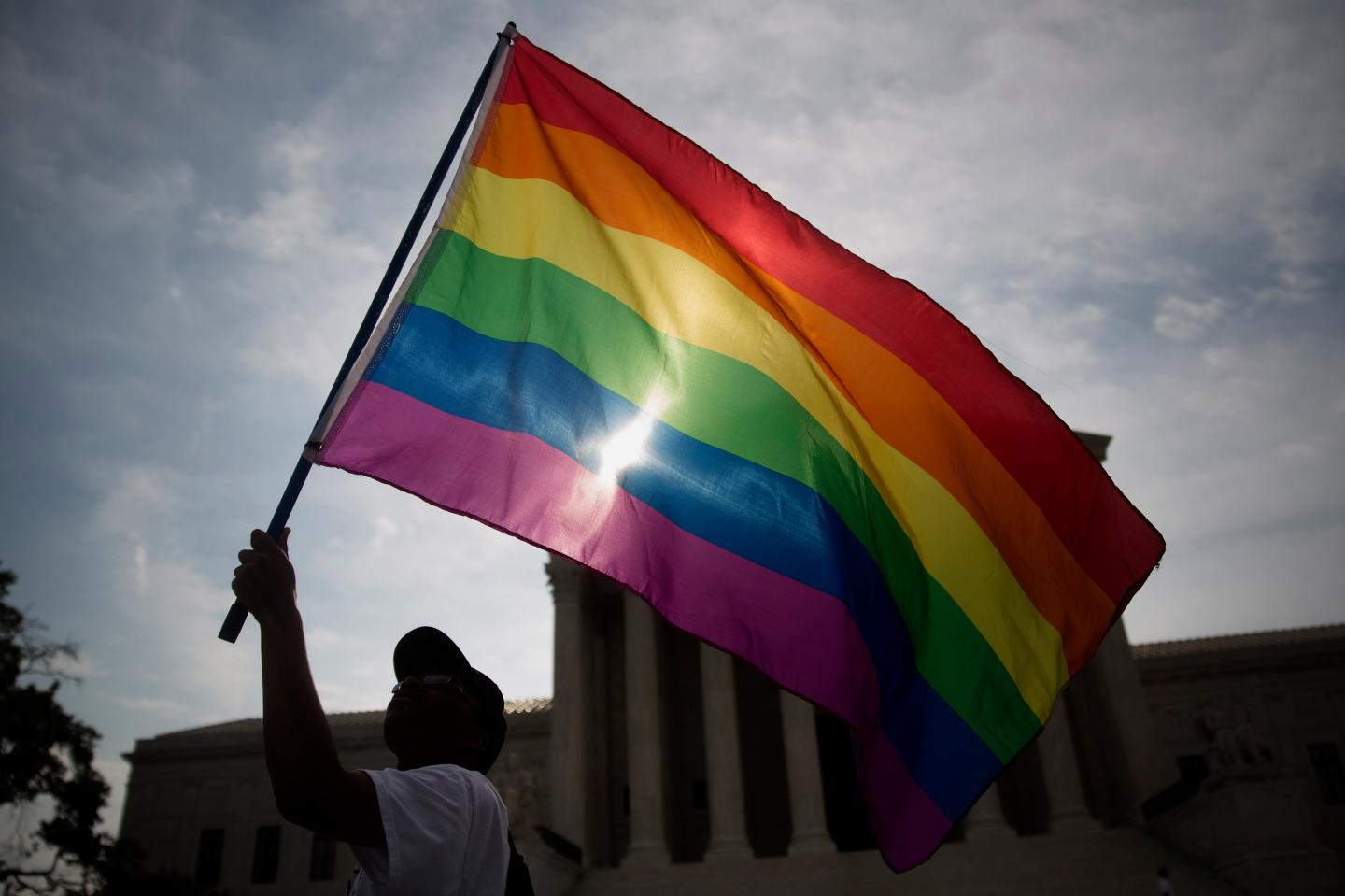 Carlos McKnight, from Washington, D.C., waves a rainbow colored flag outside the U.S. Supreme Court in Washington, D.C., U.S., on Friday, June 26, 2015. The high court will decide by the end of the month whether the Constitution gives gays the right to marry. The court's actions until now have suggested that a majority of the nine justices will vote to legalize same-sex weddings nationwide. Photographer: Andrew Harrer/Bloomberg *** Local Caption *** Carlos McKnight