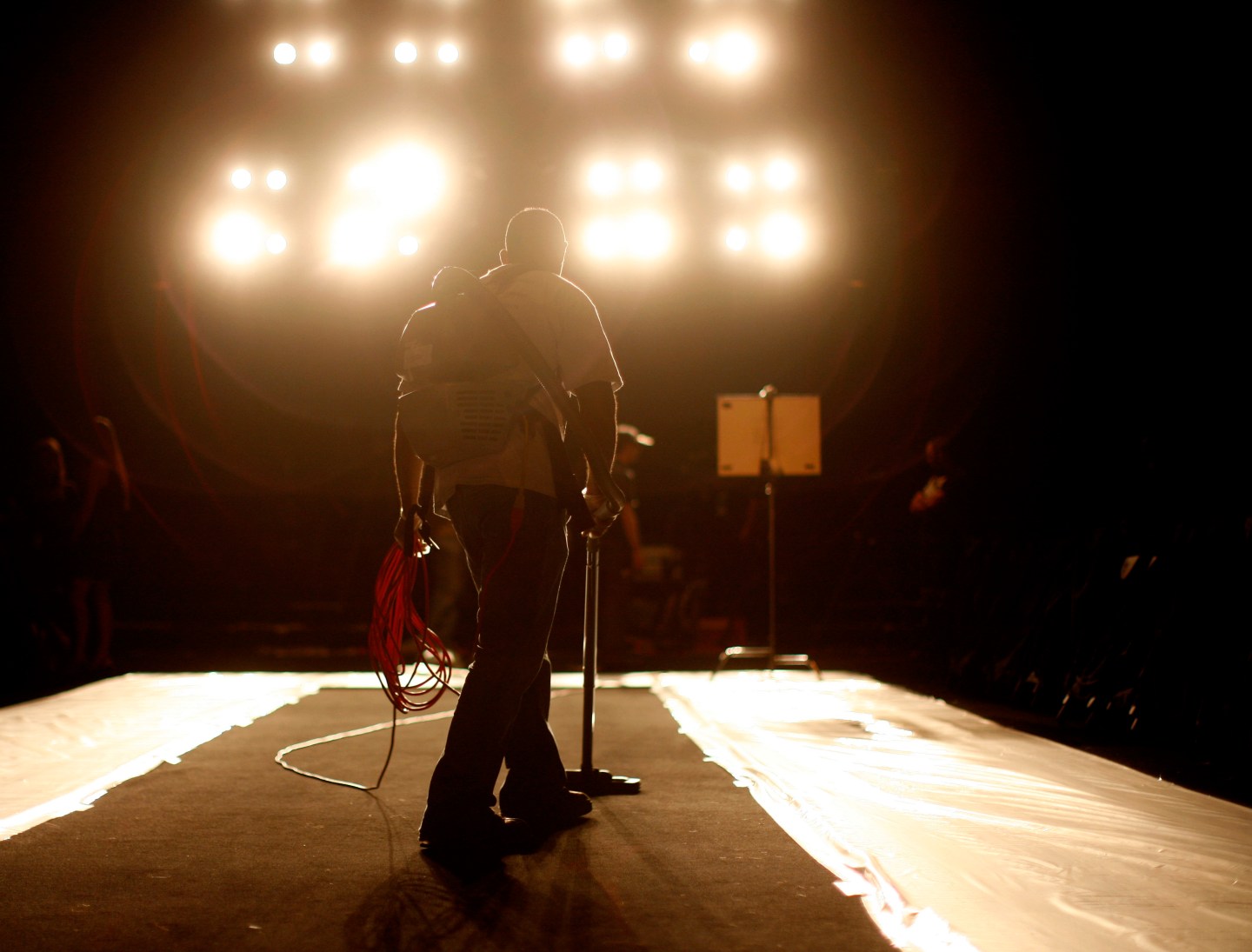 A worker vacuums the carpet before the Max Azria Spring 2008 collection during New York Fashion Week