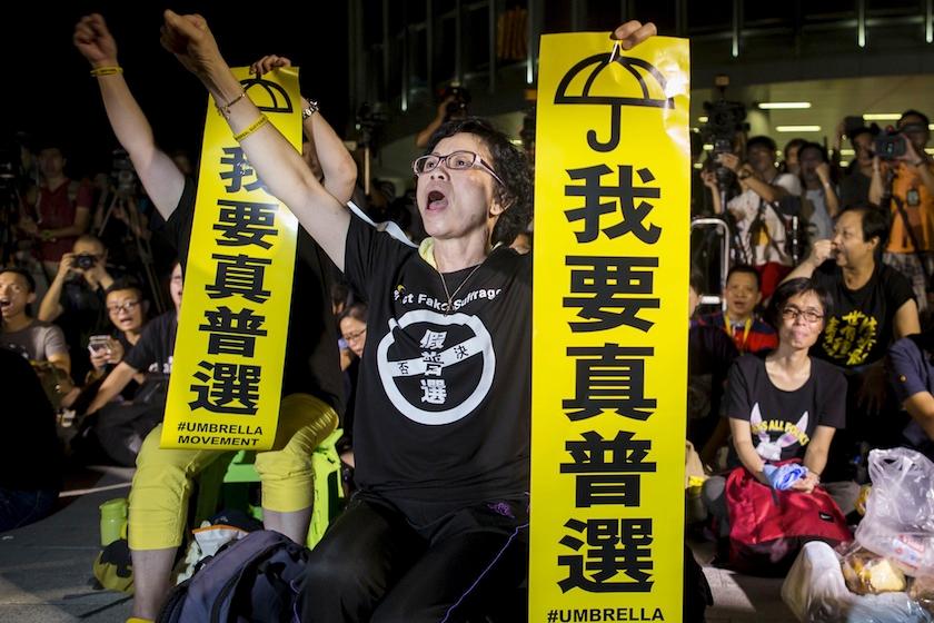 Pro-democracy protesters shout while holding banners which read "I want real universal suffrage" during a demonstration outside Legislative Council in Hong Kong