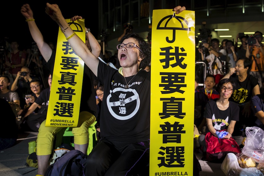 Pro-democracy protesters shout while holding banners which read "I want real universal suffrage" during a demonstration outside Legislative Council in Hong Kong