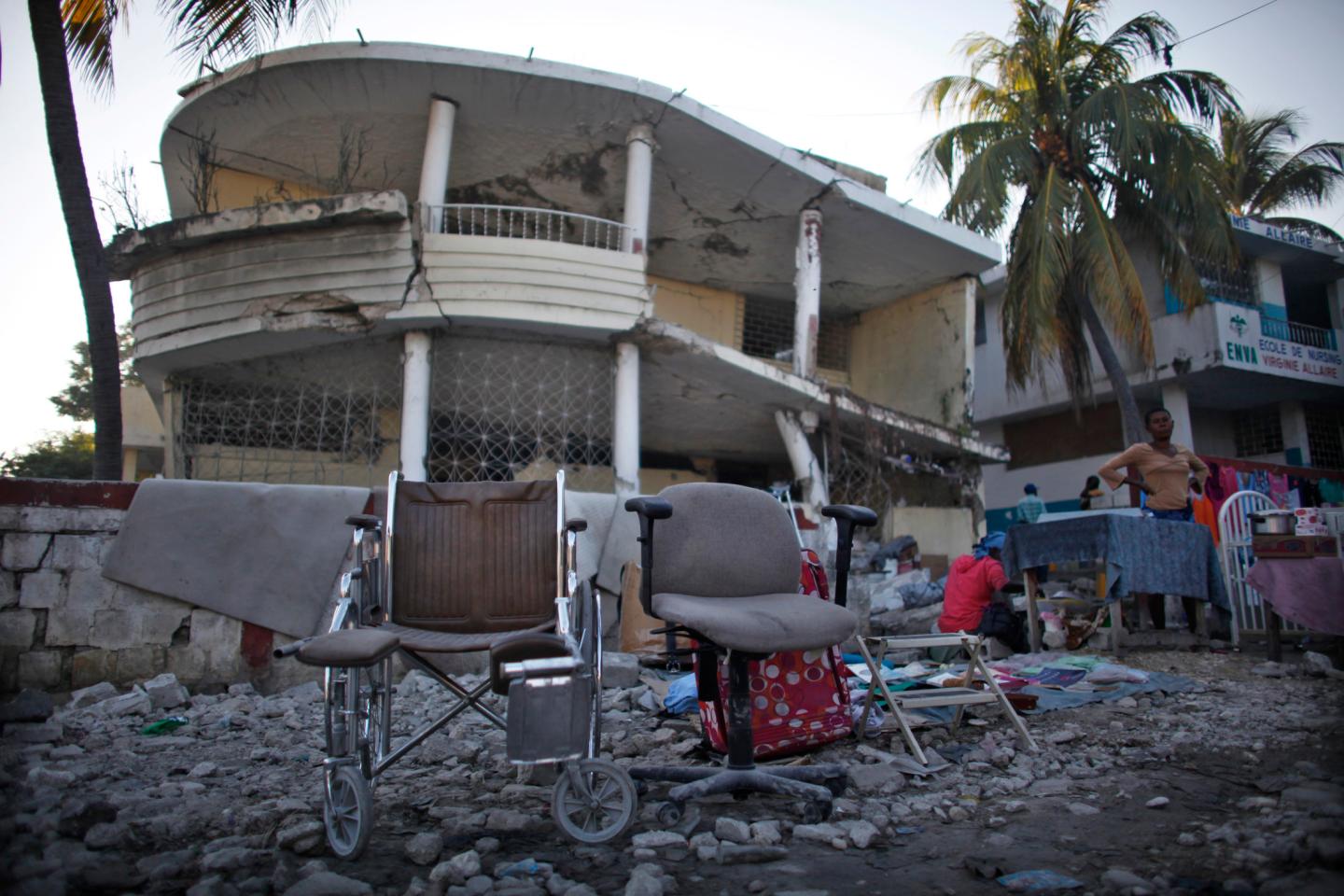 A wheelchair and other items are displayed to sell in front of a destroyed building  by the January 2010 earthquake in Port-au-Prince