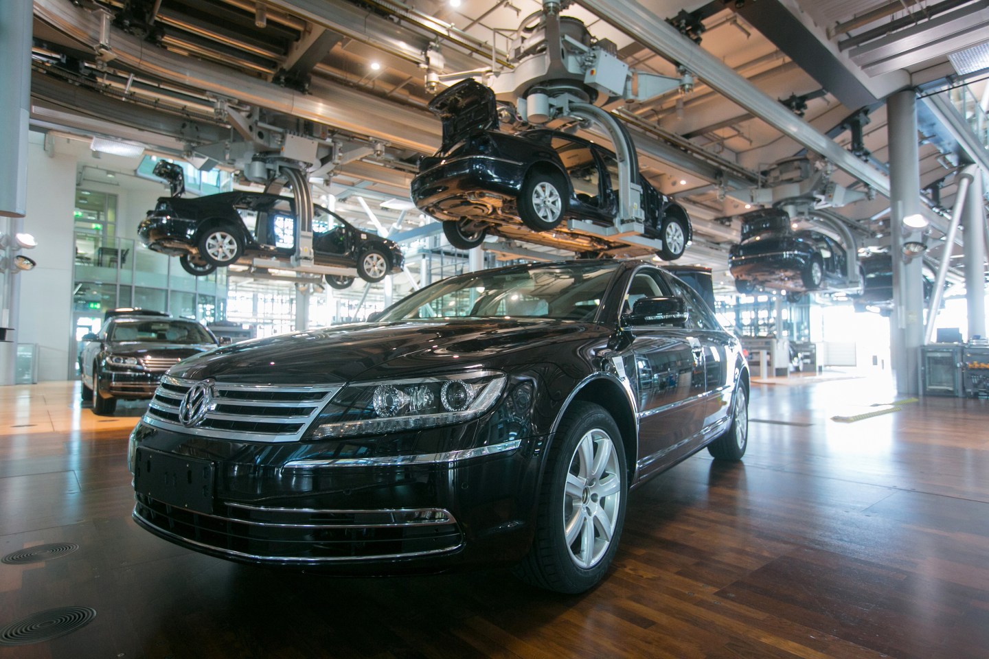 Volkswagen Phaeton automobiles move along elevated conveyors inside the Volkswagen AG factory in Dresden, Germany, on Thursday, April 9, 2015. German industrial production was bolstered by investment-goods output in February, highlighting improved confidence in the recovery in Europe's largest economy. Photographer: Krisztian Bocsi/Bloomberg