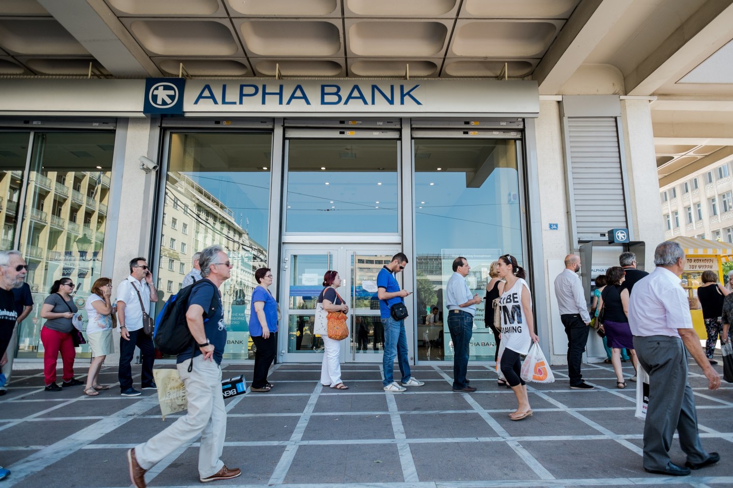 People queue at an ATM to withdraw cash in downtown Athens on July 9, 2015.