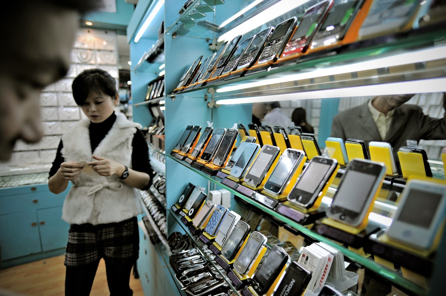 A man looking at fake iPhones displayed in a shop at a market known for counterfeit US goods and housed in the metro station connected to the Science and Technology Museum in Shanghai.
