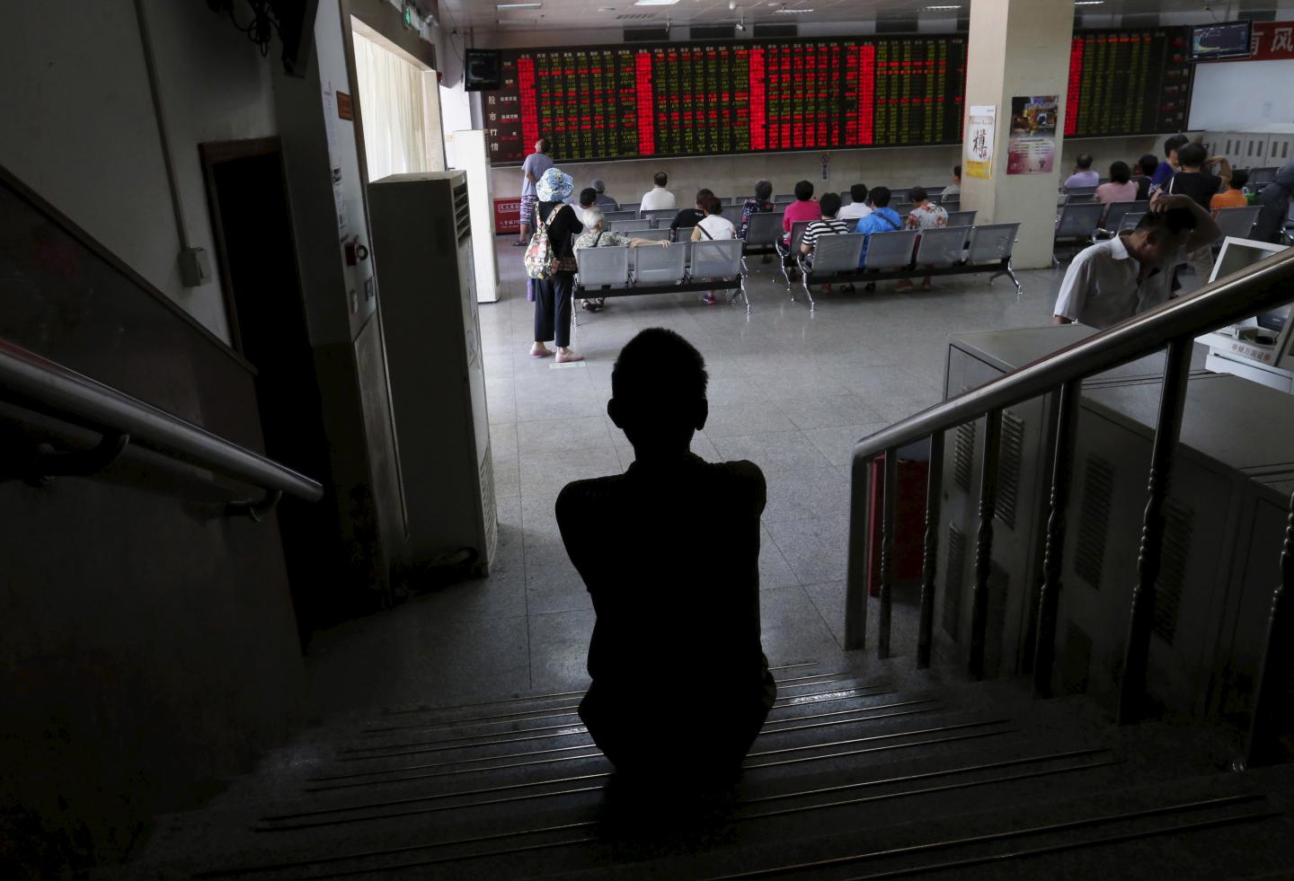 A man watches a board showing stock prices at a brokerage office in Beijing