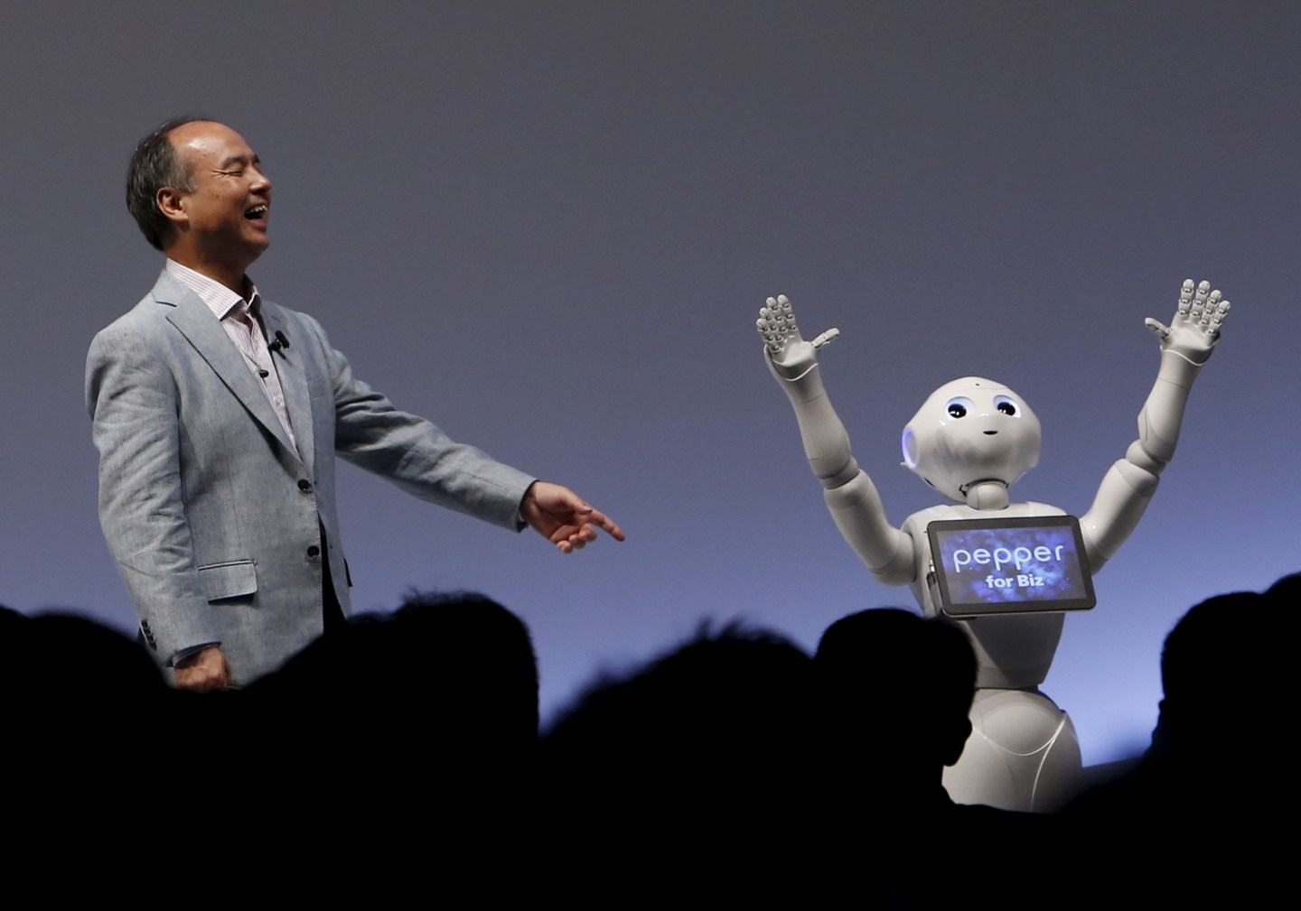 SoftBank Group Corp. Chairman and CEO Masayoshi Son reacts as SoftBank's human-like robots named "Pepper" performs during the SoftBank World 2015 event in Tokyo