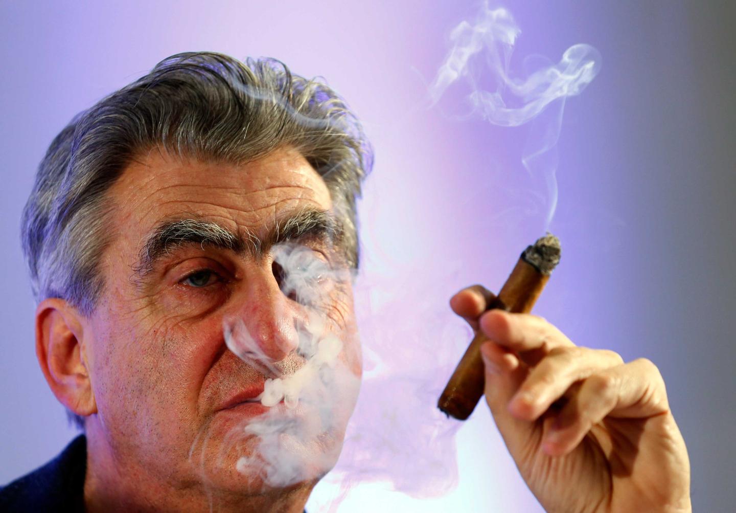 Hayek Jr Swatch Group Chief Executive smokes a cigar during the Swiss watch maker annual news conference in Plan-Les-Ouates