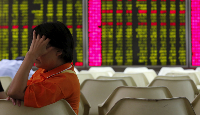 An investor sits in front of an electronic board showing stock information at a brokerage house in Beijing.