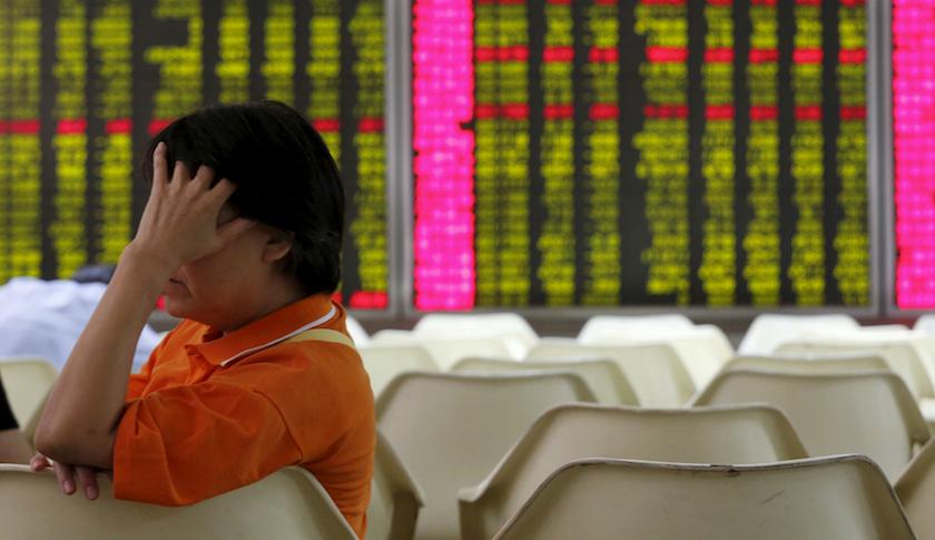 An investor sits in front of an electronic board showing stock information at a brokerage house in Beijing.