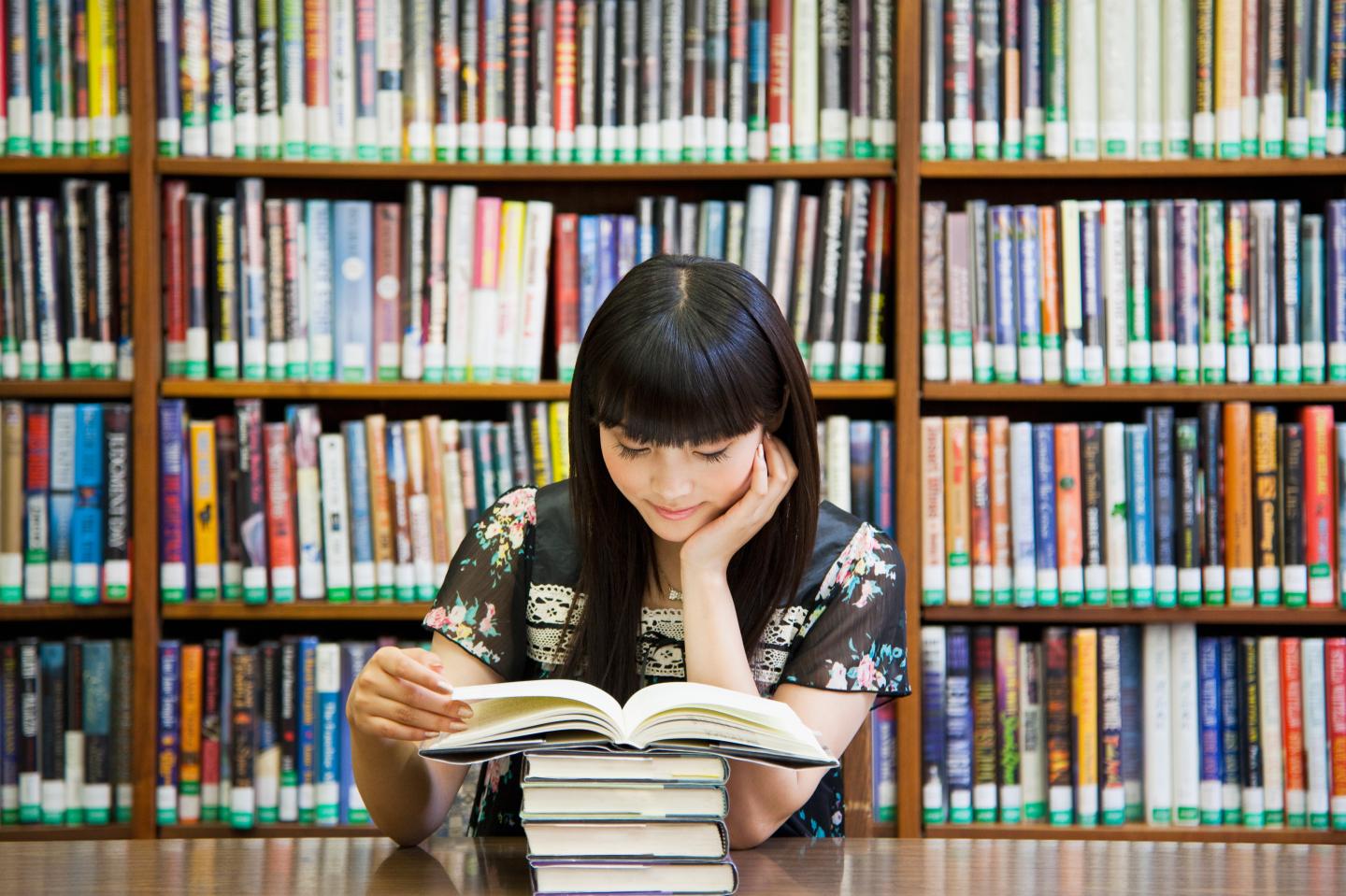 Asian woman reading book in library