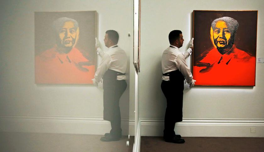 An employee with Andy Warhol's "Mao" at Sotheby's auction house in London