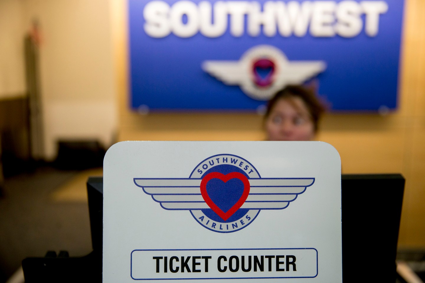 An attendant stands behind a ticket counter sign at the Southwest Airlines check-in counter at Ronald Reagan National Airport in Washington, D.C.