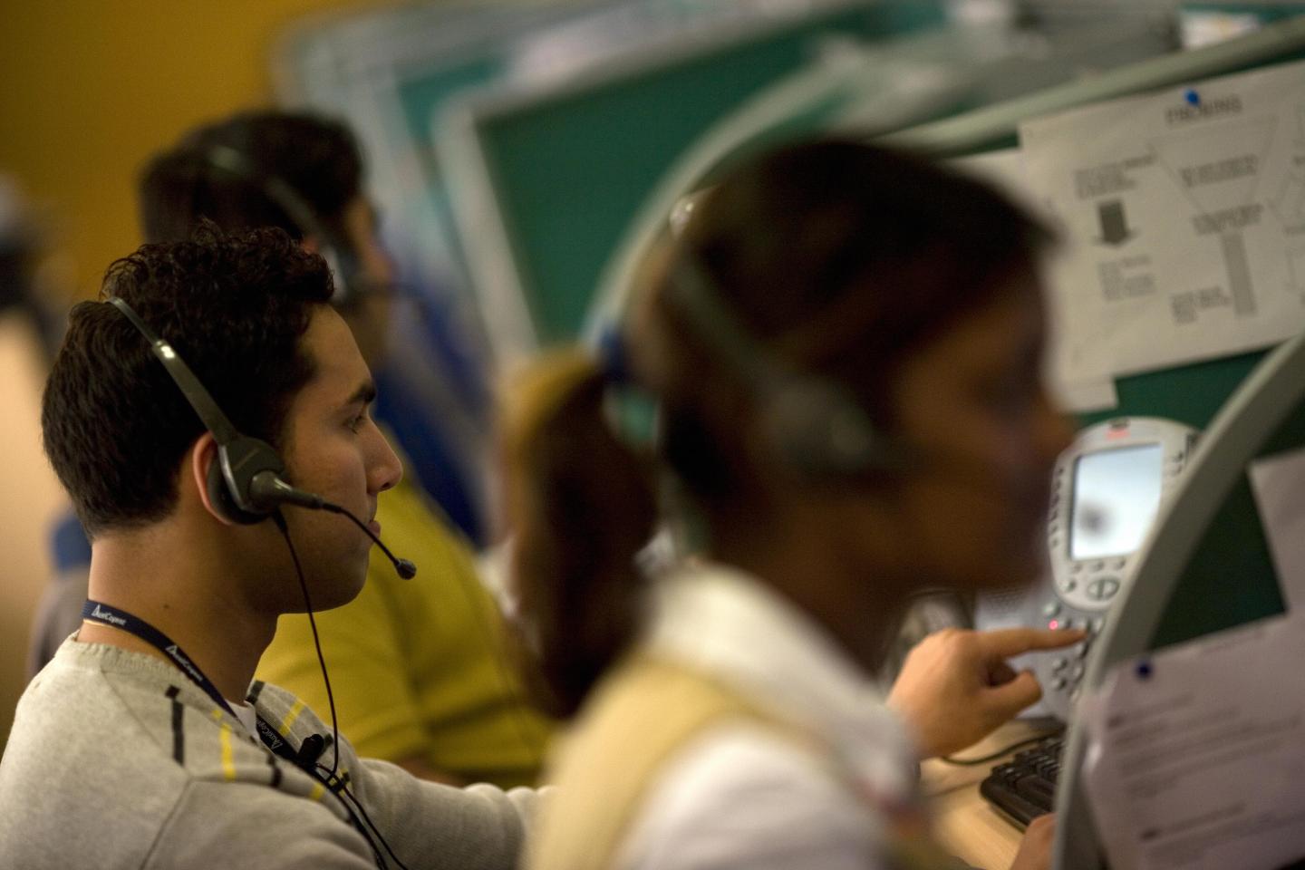 Indian workers answer telephone calls at