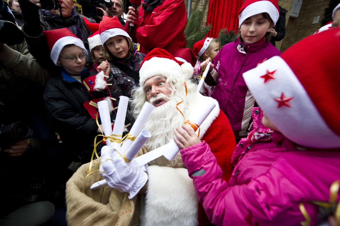 A man dressed up as Santa Claus is surro