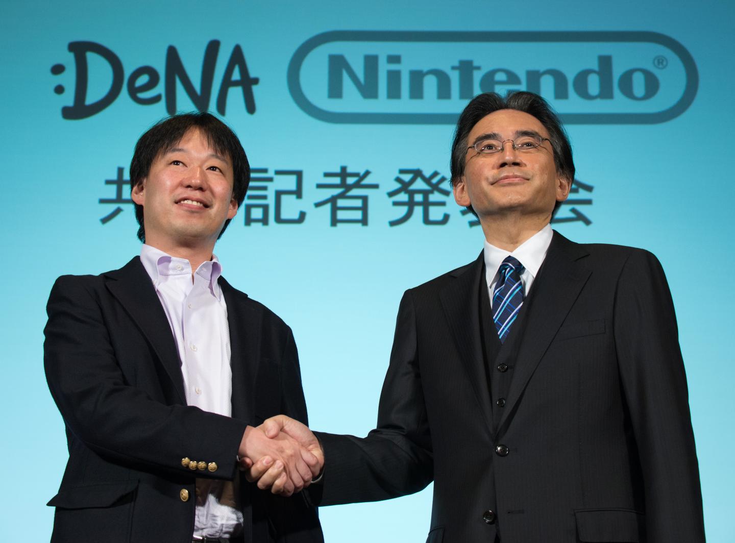 Satoru Iwata, president of Nintendo Co., right, and Isao Moriyasu, president and chief executive officer of DeNA Co., shake hands during a joint news conference in Tokyo, Japan, on Tuesday, March 17, 2015. Nintendo dropped its resistance to using its characters on mobile devices as the maker of Mario and Zelda teams with DeNA to develop new games for smartphones and tablet computers. Photographer: Akio Kon/Bloomberg *** Local Caption *** Satoru Iwata; Isao Moriyasu