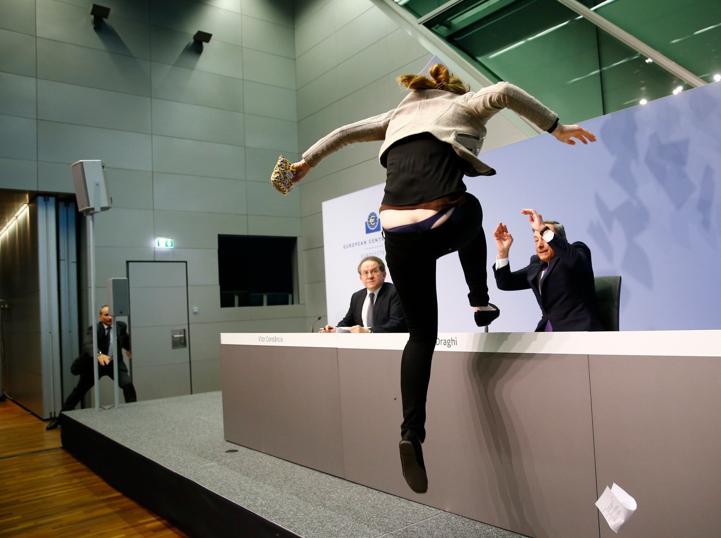 A protester jumps on the table in front of the European Central Bank President Draghi during a news conference in Frankfurt