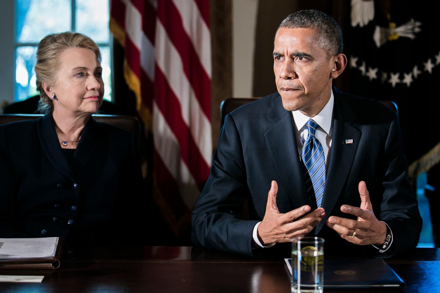 U.S. President Barack Obama, right, speaks as Department of State Secretary Hillary Clinton listens at a cabinet meeting at the White House on Nov. 28, 2012 in Washington, D.C. The president met yesterday with small business owners and today with the chief executives of major corporations in ongoing talks about the looming fiscal cliff.Photographer: T.J. Kirkpatrick/Bloomberg