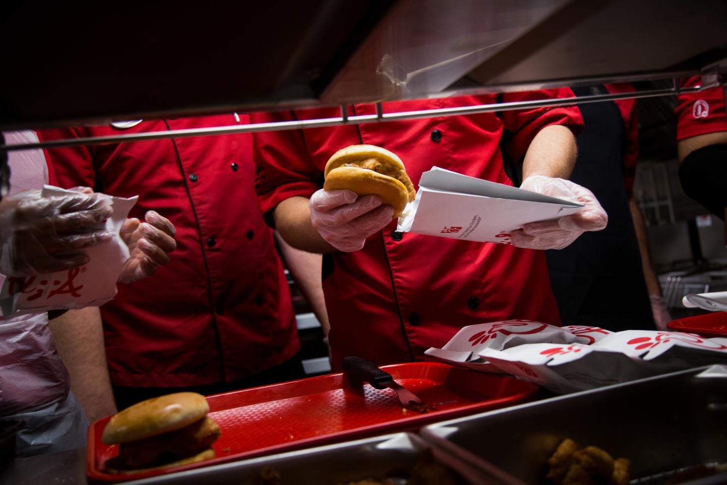 Chick-fil-A Inc. employees prepares chicken sandwiches for guests attending a friends and family event ahead of it's grand opening in New York, U.S., on Friday, October 2, 2015. Photographer: Michael Nagle/Bloomberg