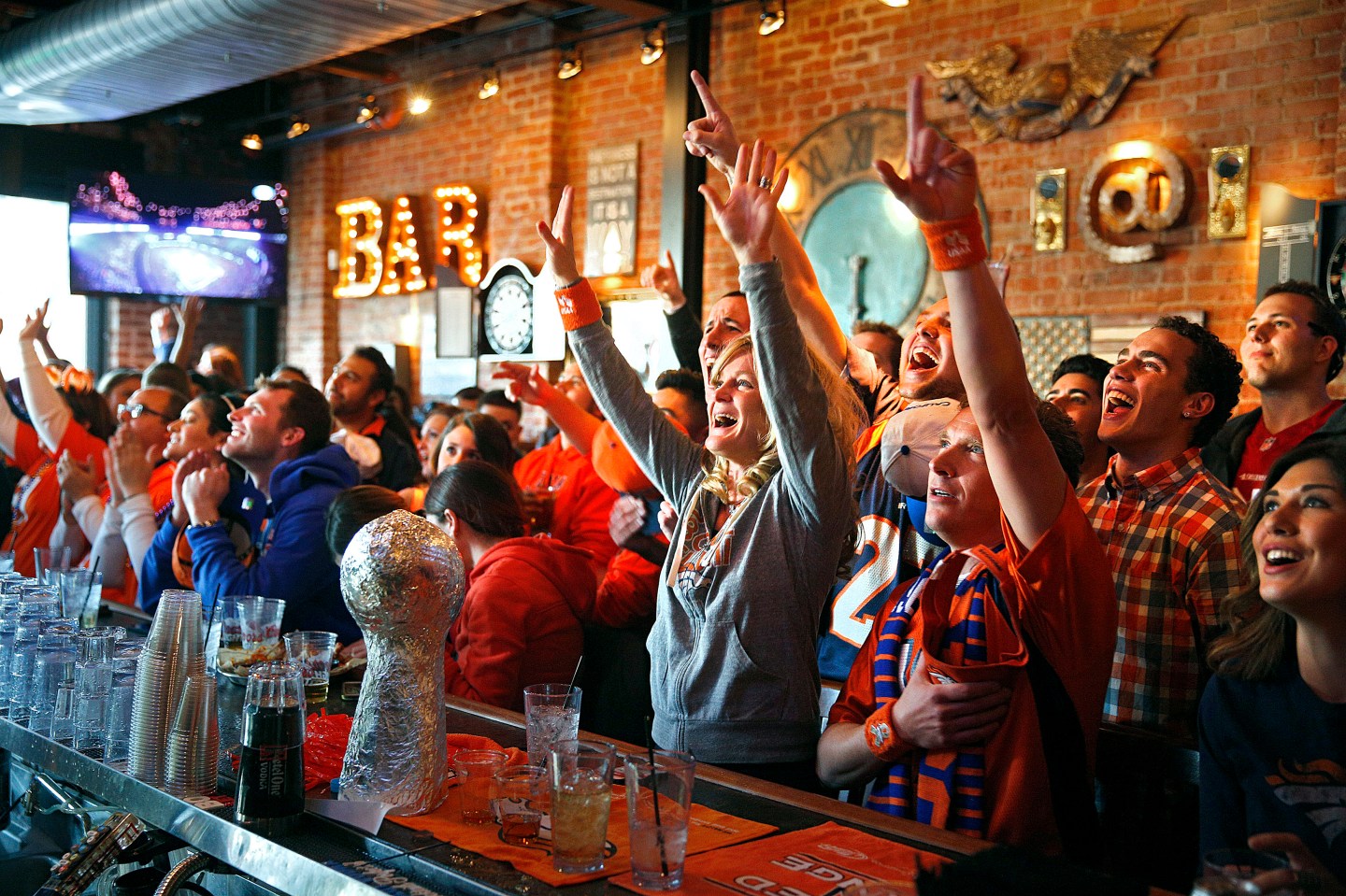 Broncos fans cheer as their team takes the field against the Seahawks while watching the NFL Super Bowl XLVIII football game at a bar in Denver