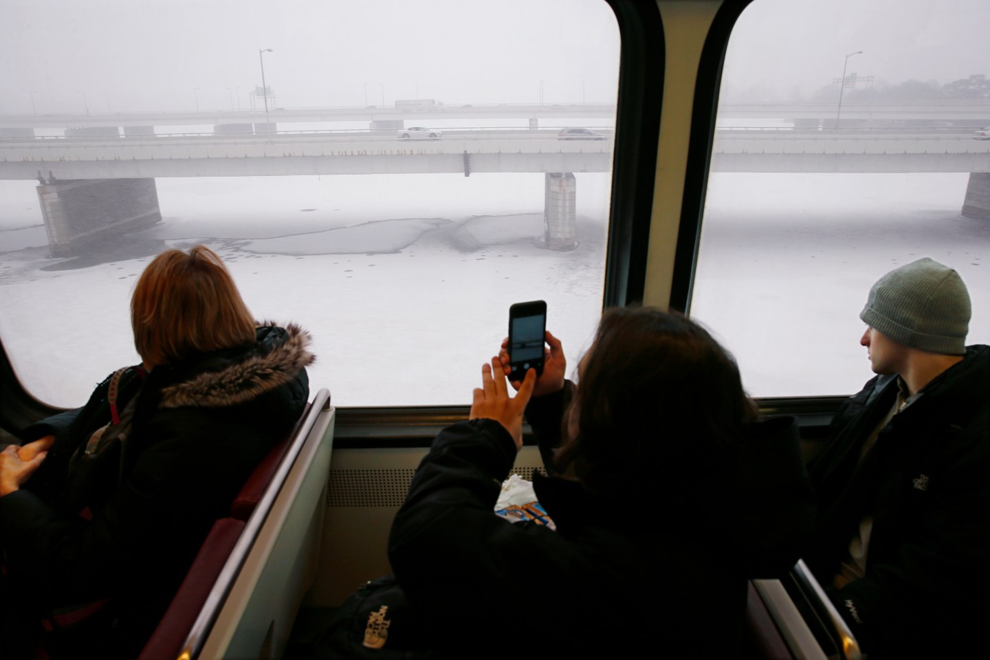 A Metro subway rider takes a picture of the snow-covered Potomac River as snow falls in Washington