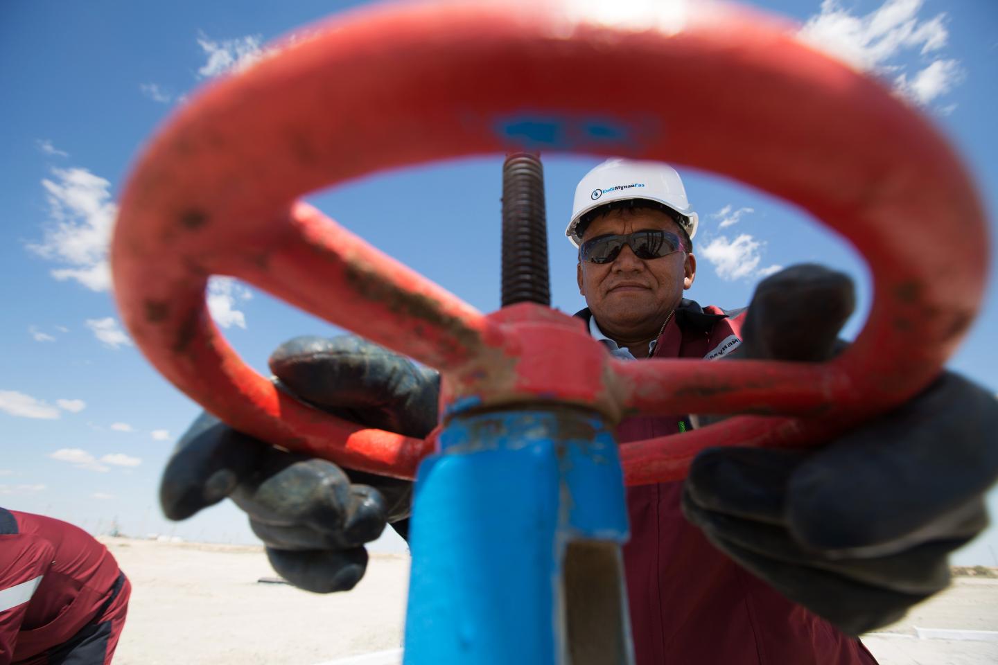 An oil worker adjusts the wheel of a flow valve on a modern oil pumping unit at an oilfield operated by Embamunaigas, a unit of KazMunaiGas Exploration Production, in Akkystau village, near Atyrau, Kazakhstan, on Saturday, July 4, 2015. The majority Muslim country is central Asia's biggest oil producer. Photographer: Andrey Rudakov/Bloomberg