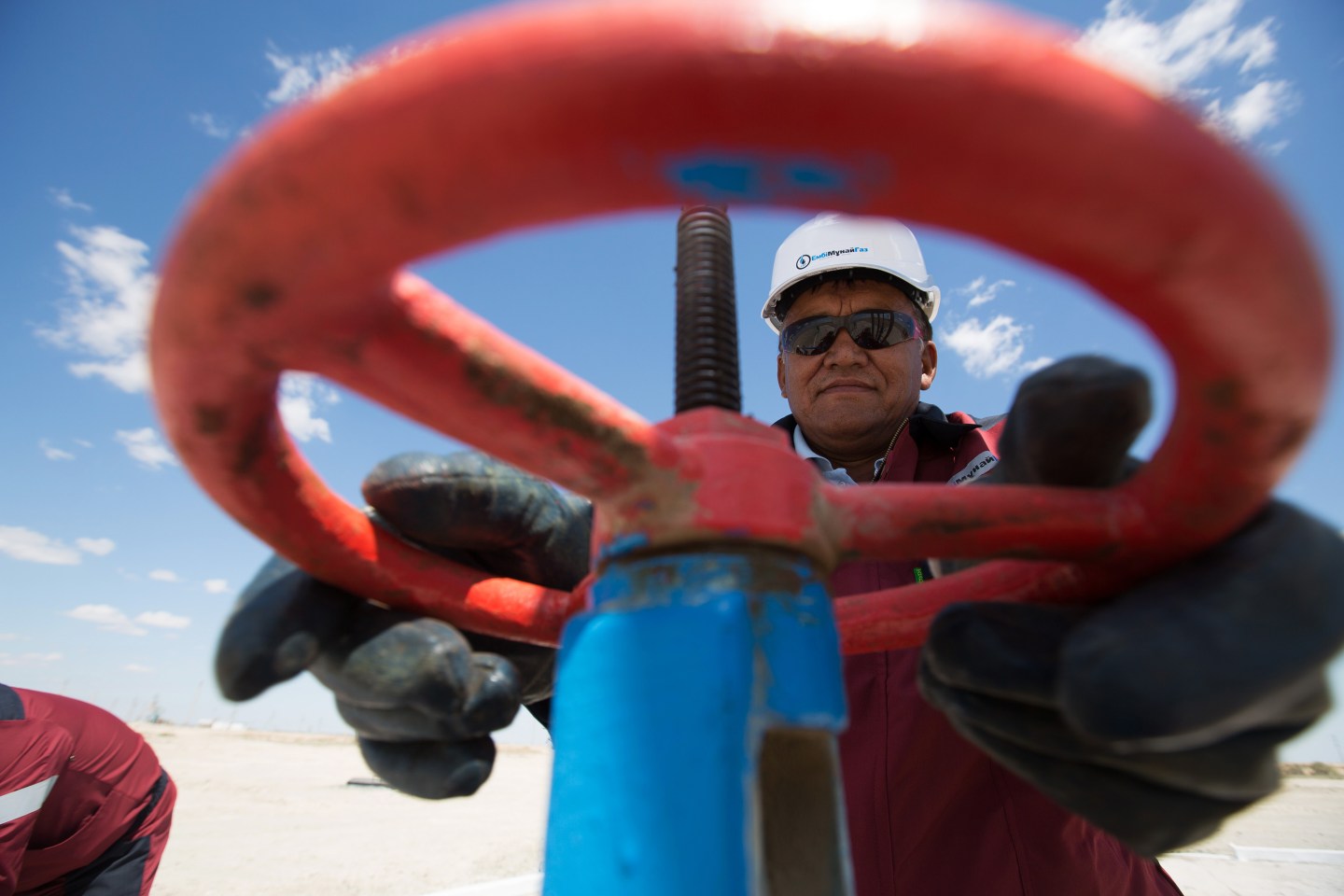 An oil worker adjusts the wheel of a flow valve on a modern oil pumping unit at an oilfield operated by Embamunaigas, a unit of KazMunaiGas Exploration Production, in Akkystau village, near Atyrau, Kazakhstan, on Saturday, July 4, 2015. The majority Muslim country is central Asia's biggest oil producer. Photographer: Andrey Rudakov/Bloomberg