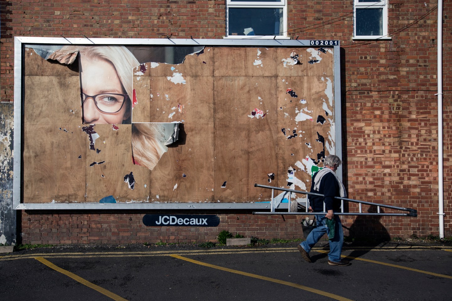 A Man Walks Past the Remains of an Old Billboard Advert