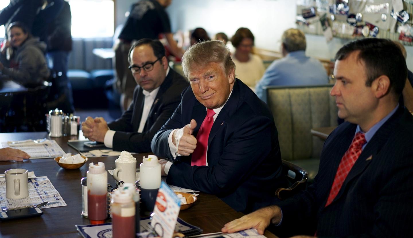 U.S. Republican presidential candidate Trump gives a thumbs up to a guest taking his picture at the Chez-Vauchon restaurant in Manchester
