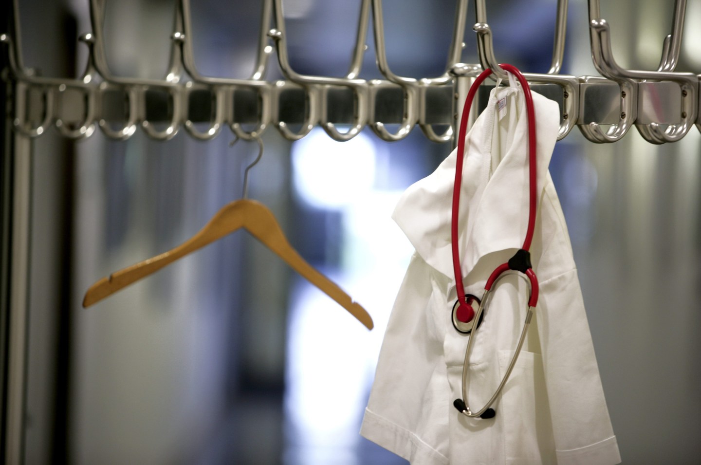 Medical scrubs and a stethoscope hanging on a coat stand.