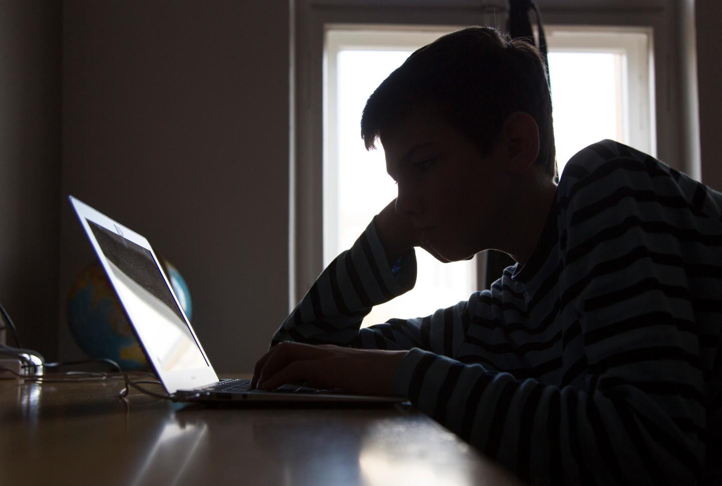 A Boy Sitting At A Laptop