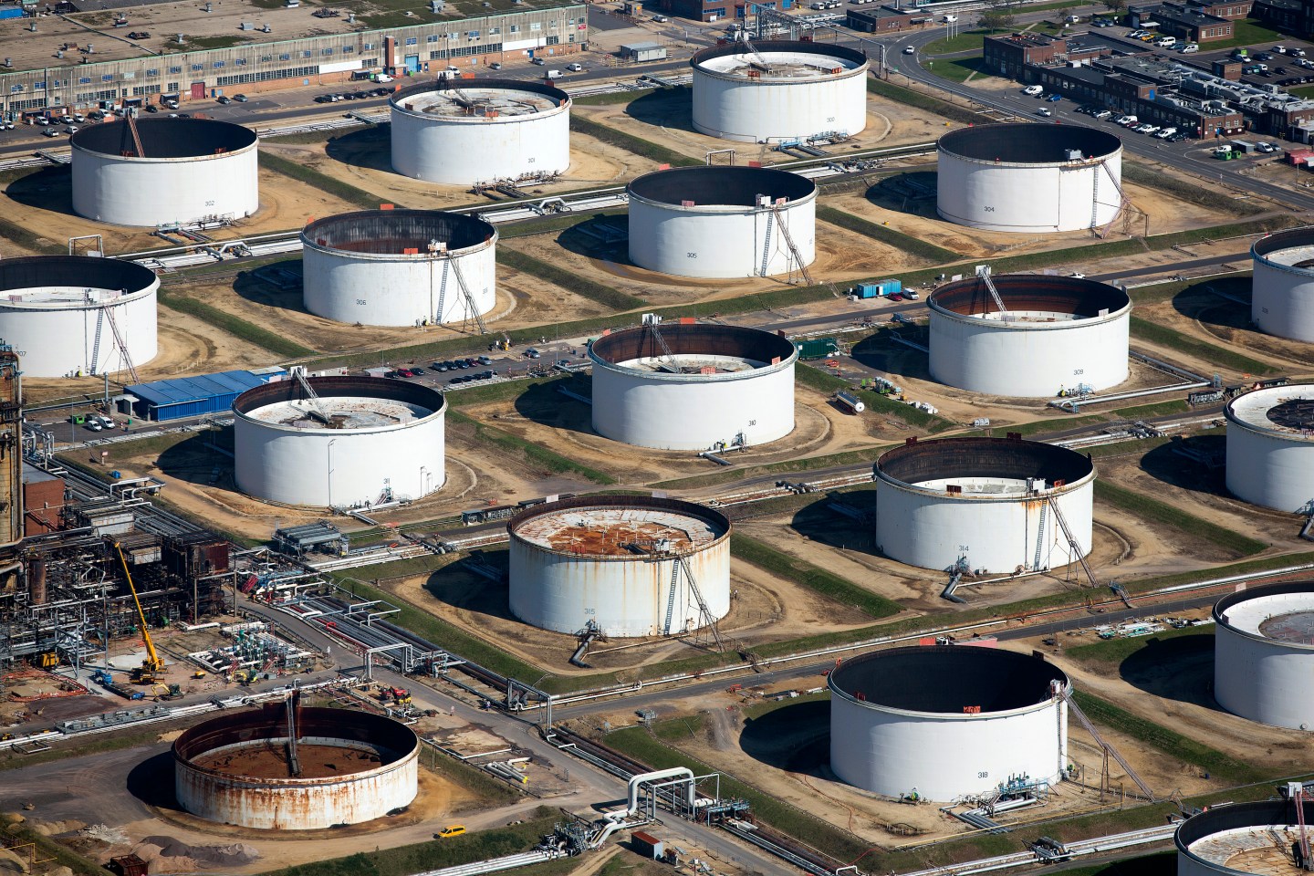Oil storage tanks sit at the Esso oil refinery, operated by Exxon Mobil Corp. in Fawley, U.K., on Friday, Oct. 2, 2015. A 50 percent drop in crude prices in the past year has hit earnings for oil and gas producers, forcing them to slash capital spending and scale back unprofitable operations. Photographer: Simon Dawson/Bloomberg