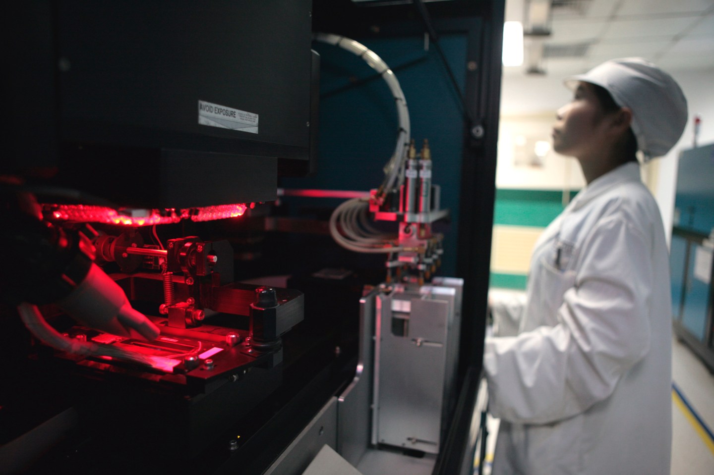 A worker controls a laser trimming machine at the chip resis