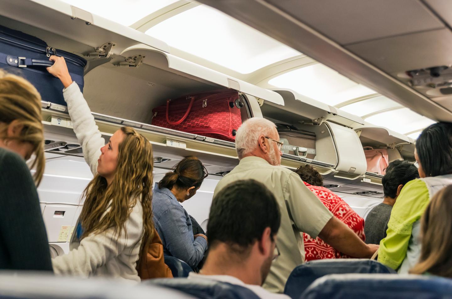 Airline travelers retrieve their carry-on luggage from