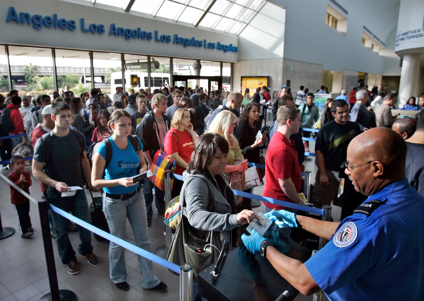 Travelers form a long security check line that is extended out of departure lounge at Los Angeles a
