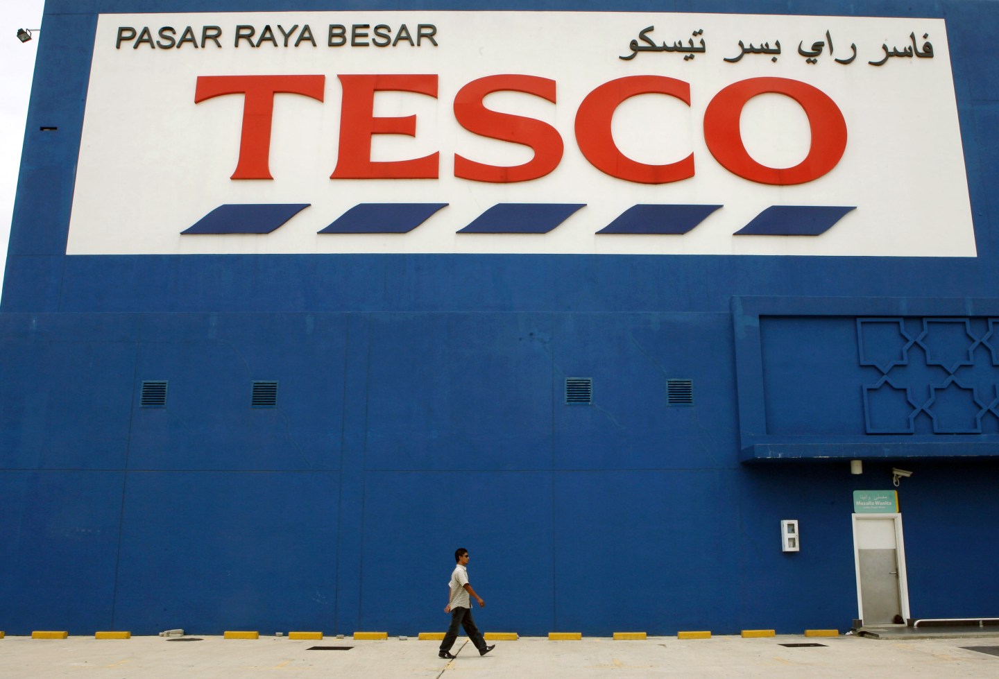 A pedestrian walks past a Tesco Plc hypermarket in Kota Bhar
