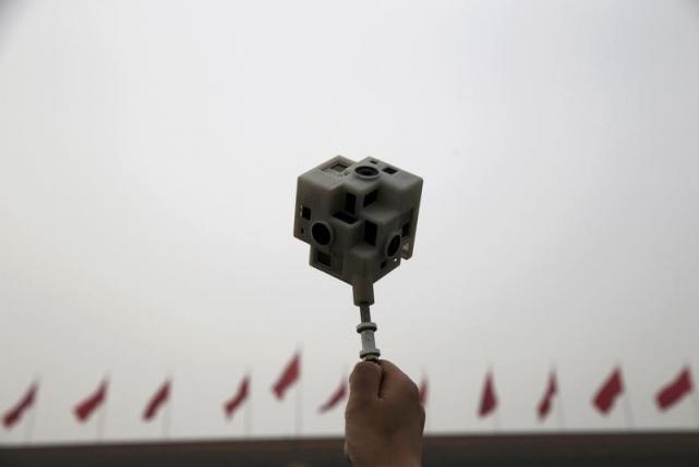 A reporter holds a 360 degree virtual reality camera in front of the Great Hall of the People before the opening session of the Chinese People's Political Consultative Conference (CPPCC), in Beijing