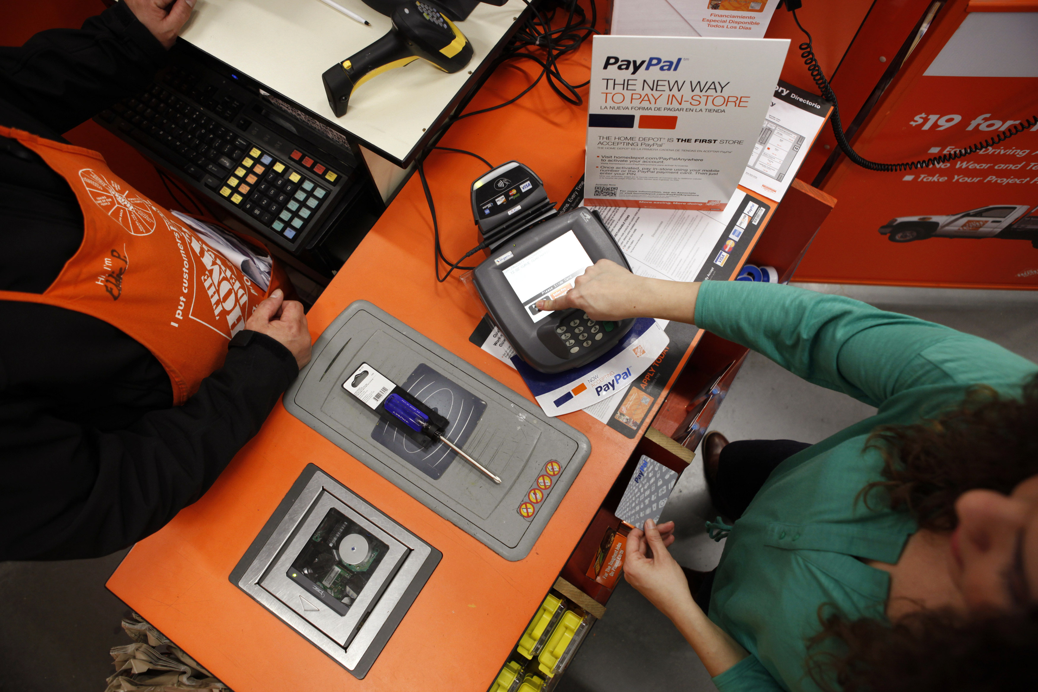 A Home Depot employee and a public relations representative demonstrate how the PayPal card works at a cashier station at a Home Depot store in Daly City