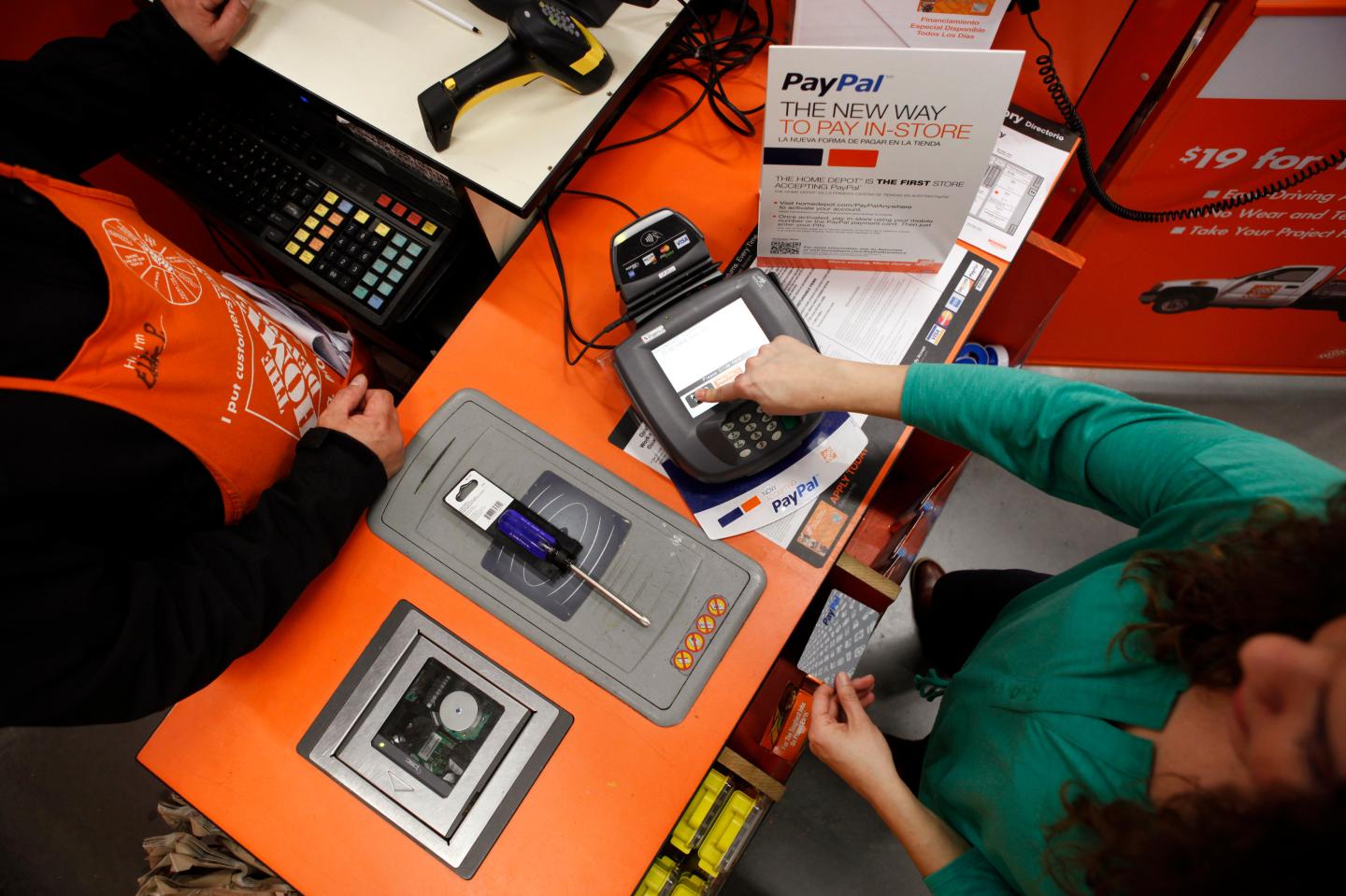 A Home Depot employee and a public relations representative demonstrate how the PayPal card works at a cashier station at a Home Depot store in Daly City