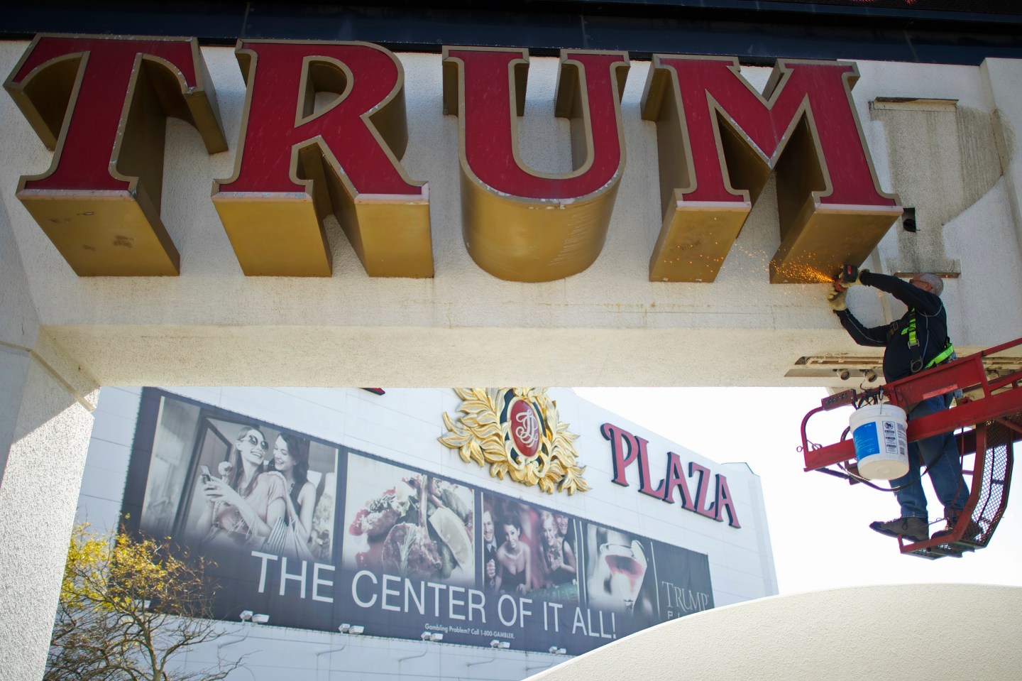 Williams, of Calvi Electric, saws mounts off the letter 'M' from the signage of Trump Plaza Casino in Atlantic City, New Jersey