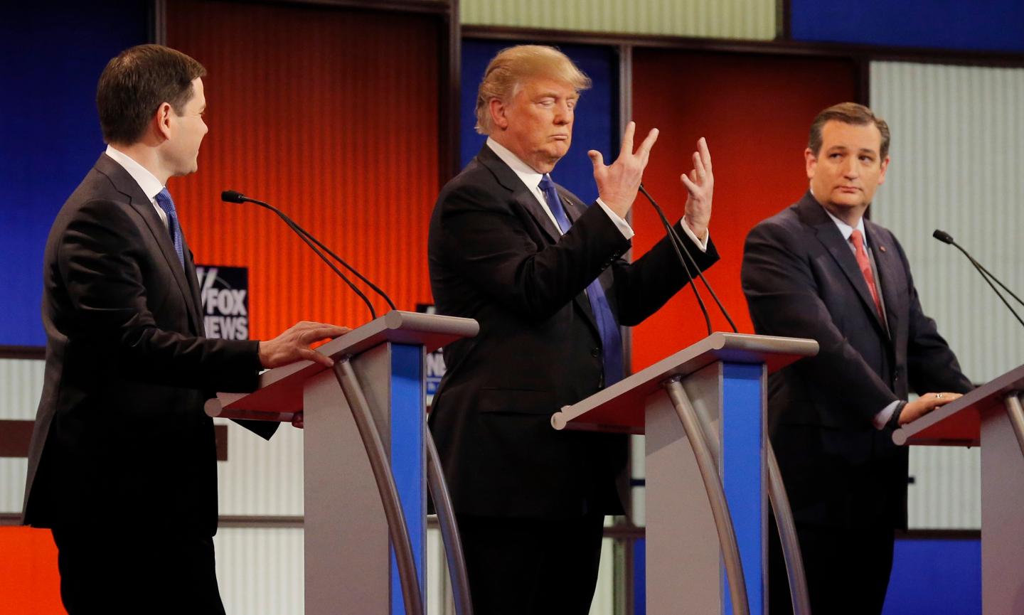 Republican U.S. presidential candidate Trump shows off the size of his hands as rivals Rubio and Cruz look on at the start of the U.S. Republican presidential candidates debate in Detroit