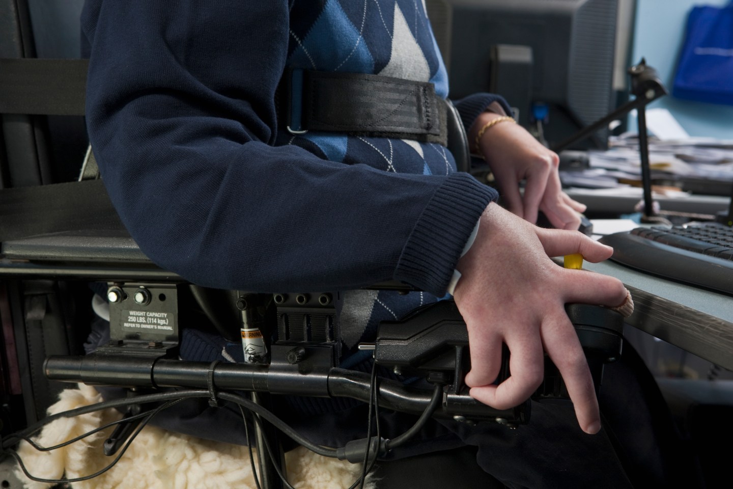 Businessman with Duchenne muscular dystrophy in a motorized wheelchair working in an office