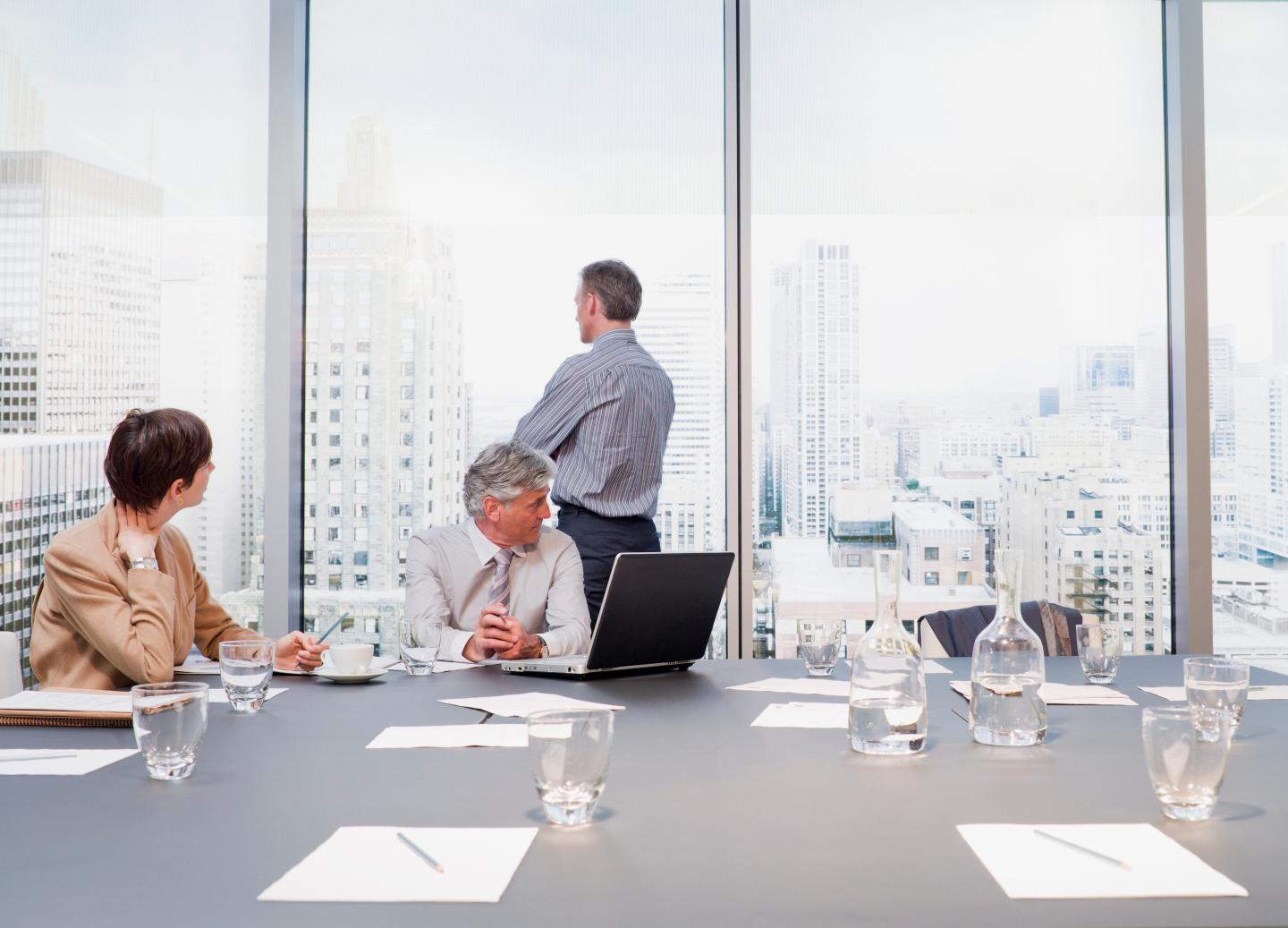 Businessman looking out conference room window at cityscape
