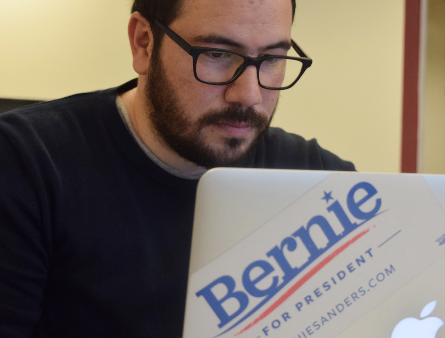 Hector Sigala poses in front of a U.S. flag at the Bernie Sanders digital team's office in Washington