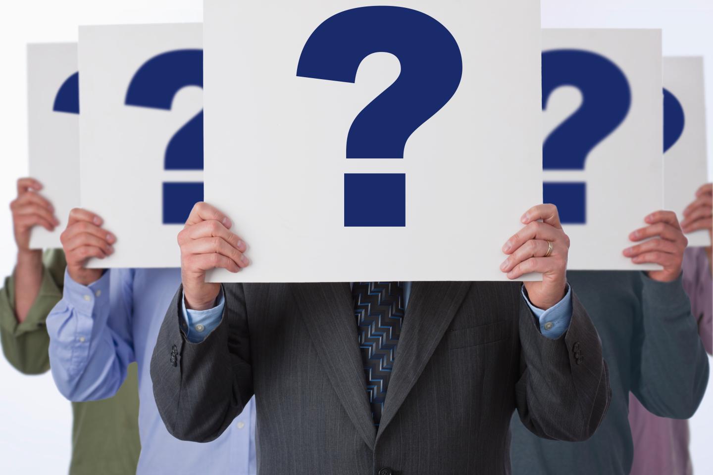 Multiplied businessman standing with question marks in fron of his face