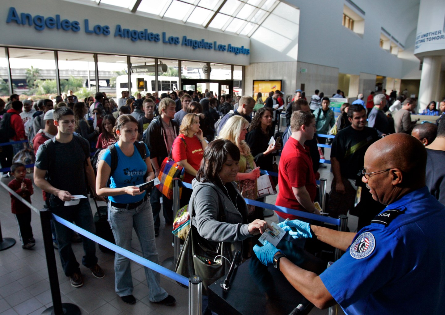 Travelers form a long security check line that is extended out of departure lounge at Los Angeles a
