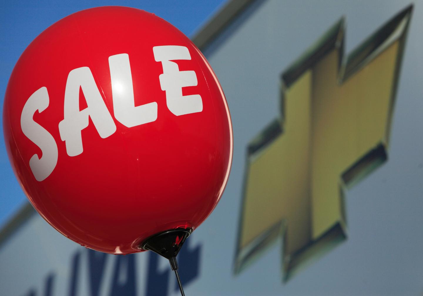 A balloon alerting consumers of a sale floats near a sign at