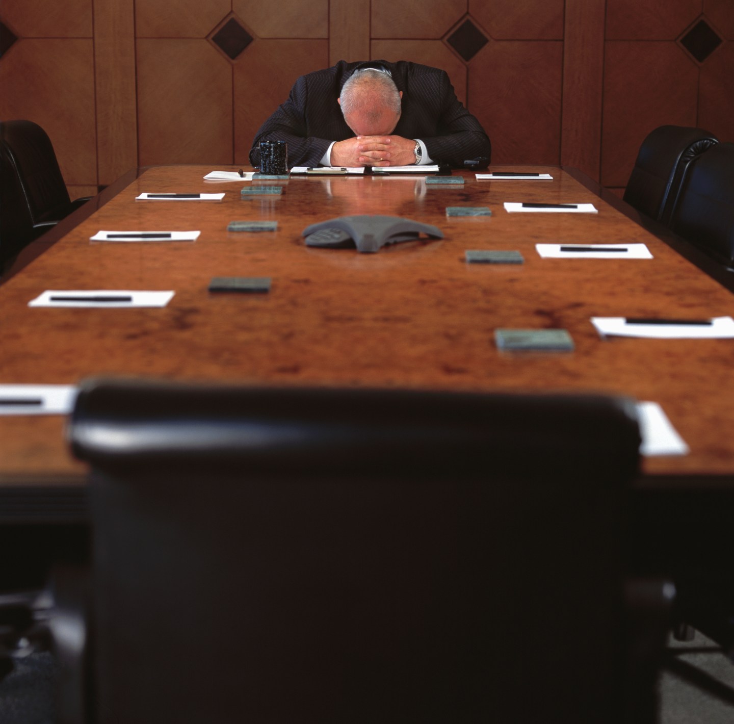 Man Sitting at Empty Conference Table with His Head Down
