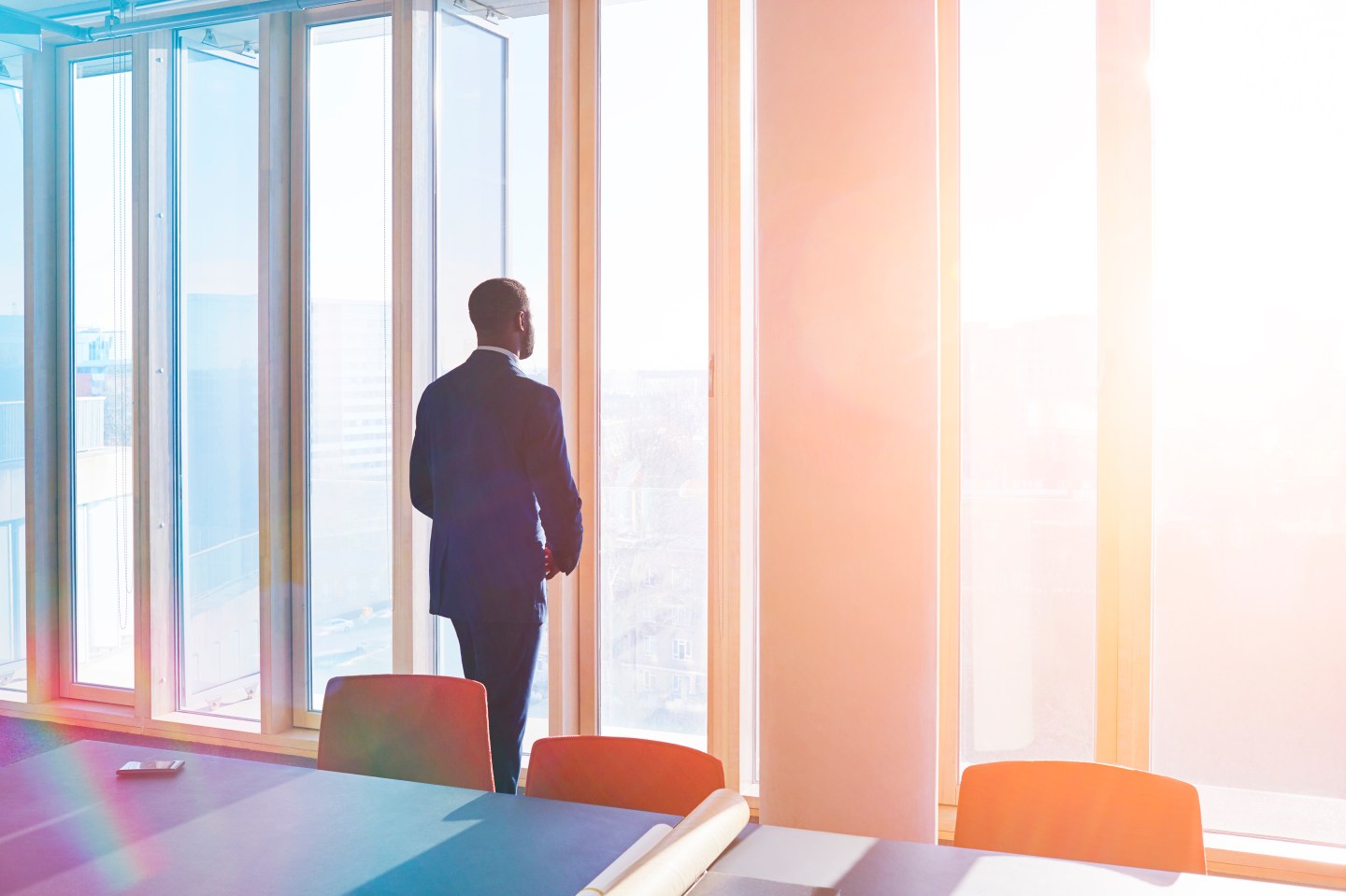 Businessman looks out of office window over city