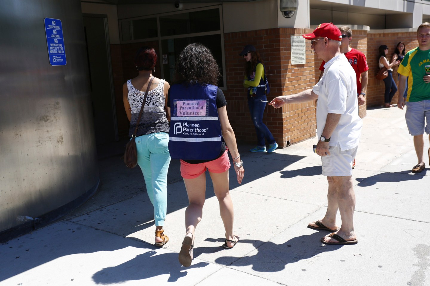 An abortion protester offers a pamphlet to a woman being escorted by a volunteer in front of a Planned Parenthood clinic in Boston, Massachusetts
